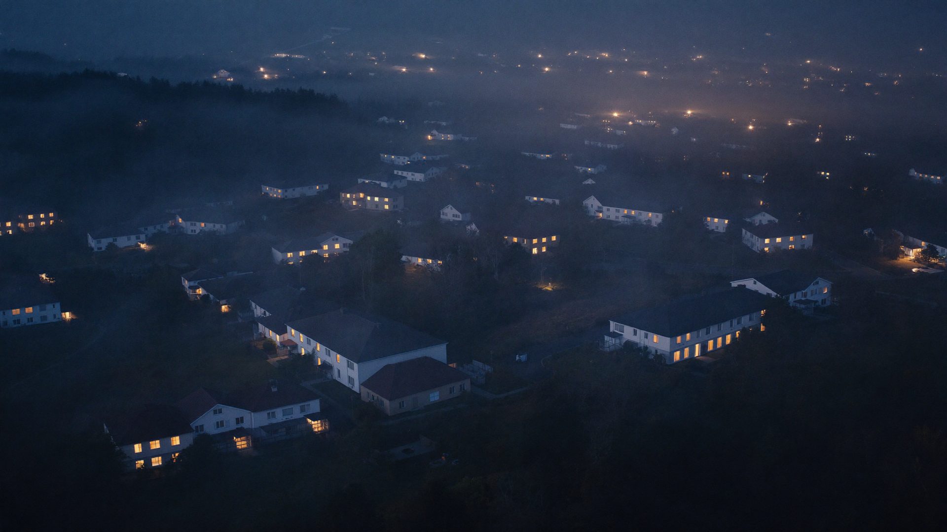 Dusk aerial view of a lit residential neighborhood
